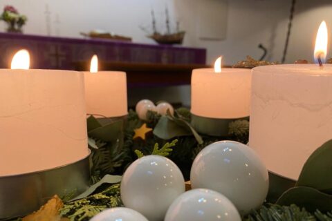 Etualalla neljä kynttilää palamassa, taustalla Hampurin merimieskirkon alttari.