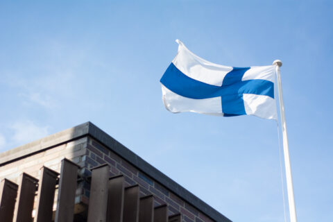 Liehuva Suomen lippu sinistä taivasta vasten