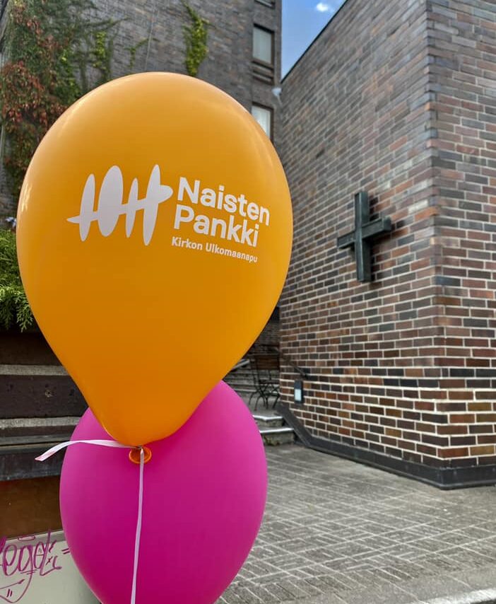 Naisten pankin värikkäitä ilmapalloja, taustalla Hamprin merimieskirkon tiiliseinä