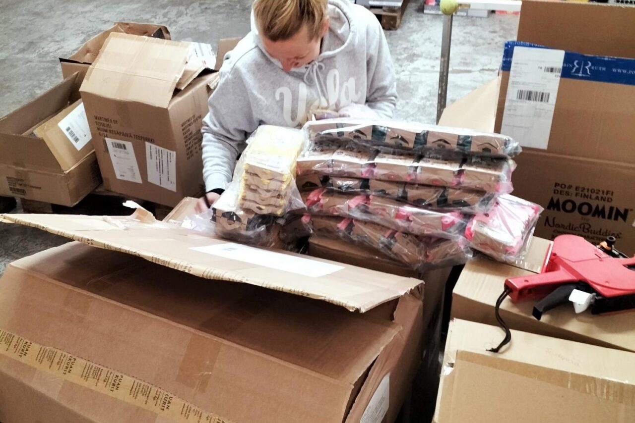 Vaalea nainen avattujen pahvilaatikoiden keskellä.