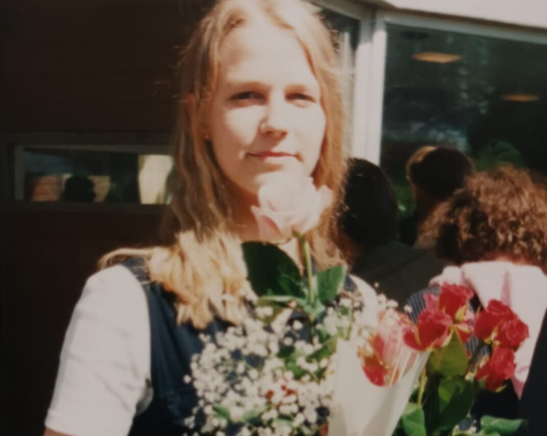 Nuori nainen kukkia sylissään. On hänen rippipäivänsä kesällä 1996