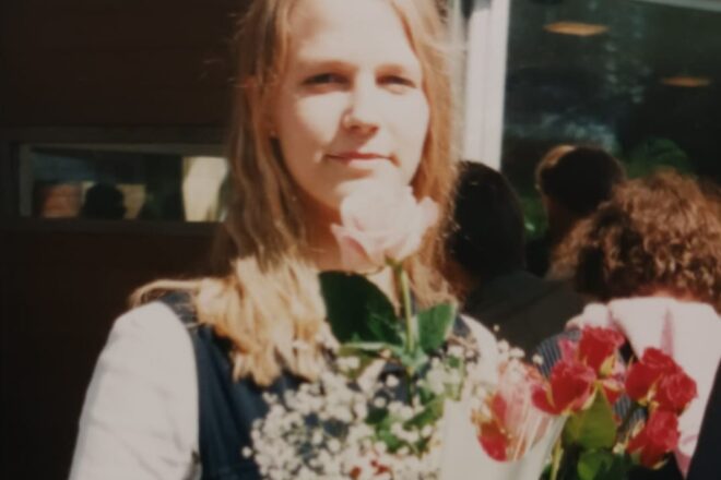 Nuori nainen kukkia sylissään. On hänen rippipäivänsä kesällä 1996